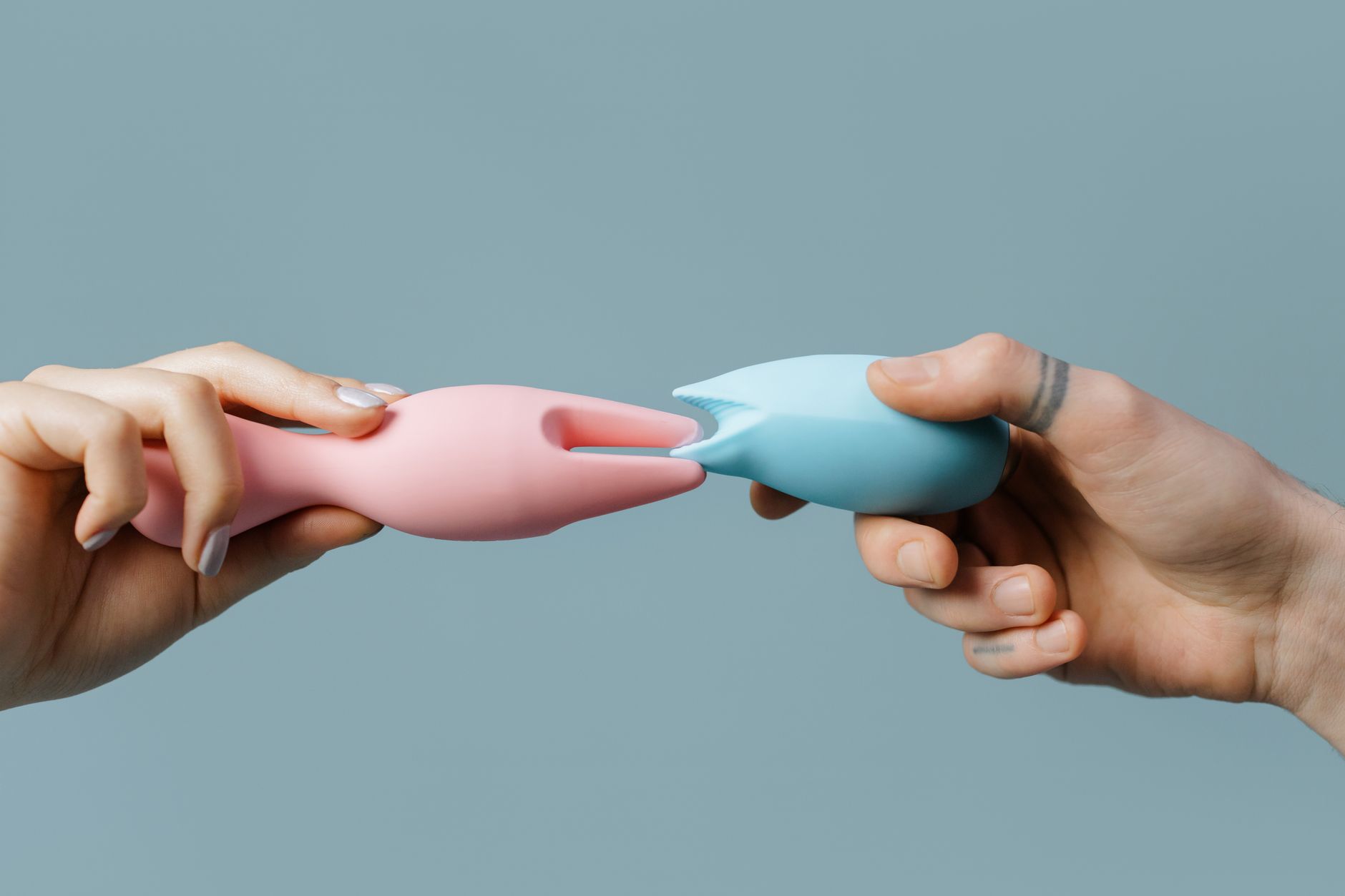 Hands holding pastel-colored silicone toys, including lemon vibrators for exploring pleasure.