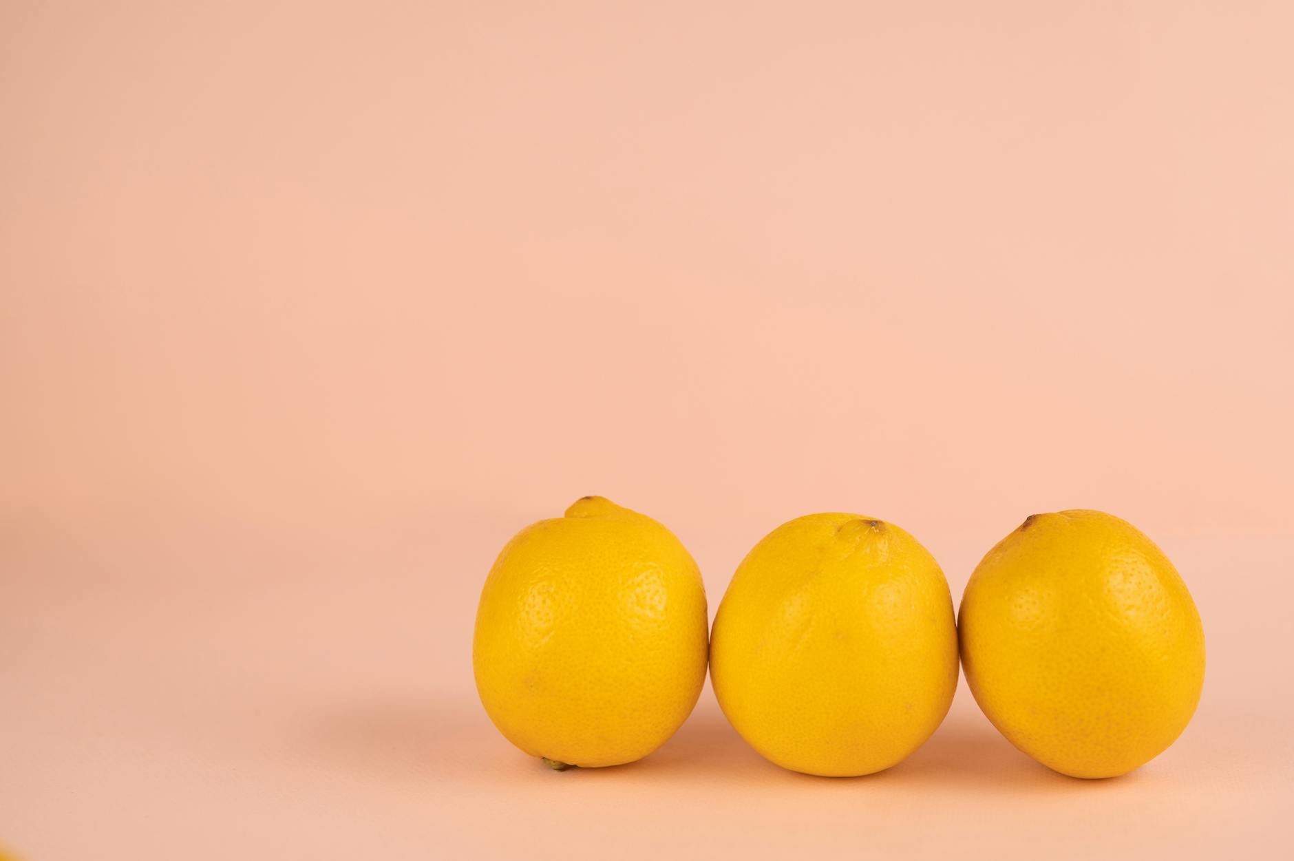 Hand holding a fresh lemon against a vibrant yellow background, symbolizing bright and refreshing intimate moments